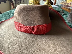A lovely and scarce **Cameroon Schutztruppe Südwester**, unfortunately missing its original sweatband. Believed to be an officer’s example, as the quality is better than that normally seen on other ranks’ examples, and the cockade is of an unusual pattern.

The Südwester was perhaps the most famous and distinctive headgear of the Schutztruppe. It was worn by all ranks on most occasions in South West Africa, as well as on home duties in Germany. In East Africa and Cameroon it was less widely used, often being replaced by the tropical helmet while on active service.

Made from grey felt, the hat was turned up on the right-hand side and secured by a large metal Imperial cockade in black, white and red. The hatband ribbon and edging varied according to colony: blue for South West Africa, white for East Africa and red for Cameroon.

Officers’ and senior NCOs’ Südwesters were often privately tailored and were generally of better quality and more elaborate than standard other ranks’ examples, sometimes featuring wider ribbons, edging and larger or more elaborate cockades. On some examples, silver was used in place of white.

The Südwester was a source of pride for the Schutztruppe as well as a practical piece of kit, providing shade from the sun during the day and even being rolled up for use as a pillow at night.

Being offered for sale on consignment.