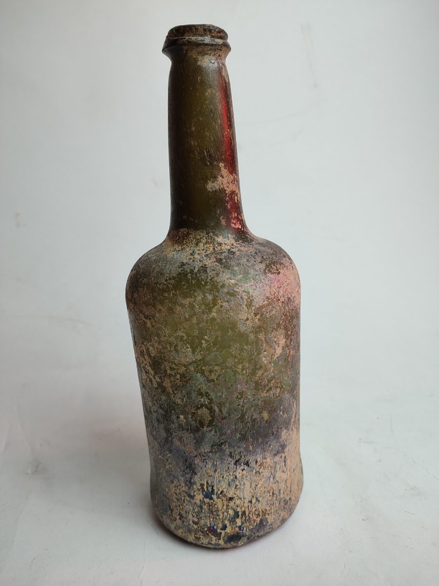 Discover our 18th century green glass wine bottle, dated 1790-1820, standing at 27 cm tall. Shop now for this unique, excavated and well-preserved piece of history!