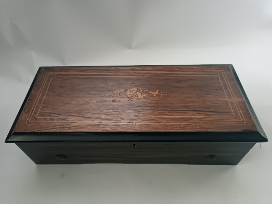 Discover our Victorian wooden Swiss music box with stunning satinwood inlay. Easy to use with start/stop function and change lever. Measurements: 52x24x15cm. Shop now to bring this musical charm to your home!