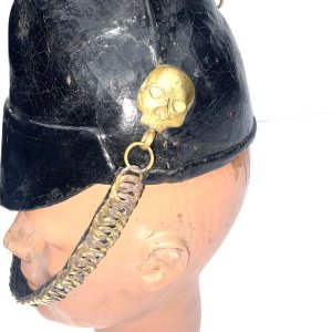 17th lancers foul weather officers lance cap, light weight black leather covered helmet having gilt metal skull side bosses holding leather backed linked gilt brass chin chain. Leather covered dome fitting to represent the rosette. Interior has the leather sweatband and crimson lining. Overall conditions quit good fantastic item from my late fathers collection,