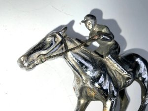 Super item from the roaring twenties comes this fantastic car mascot in the shape of a jockey at gallop on horse, overall conditions good, length of 15 cm height 11 cm width being 34 mm,