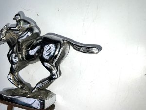 Super item from the roaring twenties comes this fantastic car mascot in the shape of a jockey at gallop on horse, overall conditions good, length of 15 cm height 11 cm width being 34 mm,