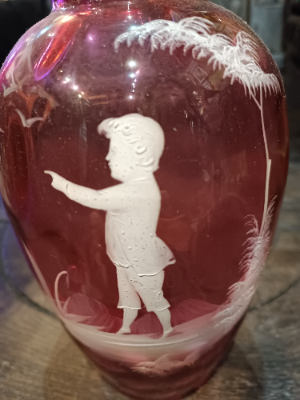 A large Mary Gregory cranberry glass vase depicting a boy painting to the birds. Size  25.5 cm high.