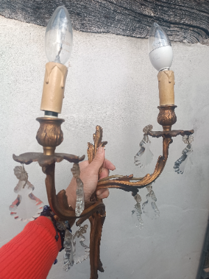 A set of three rococo revival wall sconces in gilt metal, with foliage shaped wall mounts and arms, and foliate drip trays from which leaf shaped cut glass drops hang. 
Two wall sconces with triple arms and the other with twin arms.
Size approx 48 cm high x 32 cm wide for the sconce with three arms.
