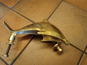 A  dolphin shaped brass door knocker completed with bolt fittings. Size 17 cm long.