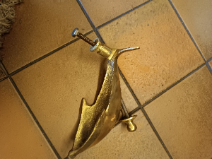 A  dolphin shaped brass door knocker completed with bolt fittings. Size 17 cm long.