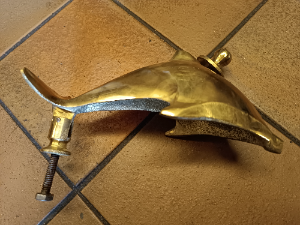 A  dolphin shaped brass door knocker completed with bolt fittings. Size 17 cm long.