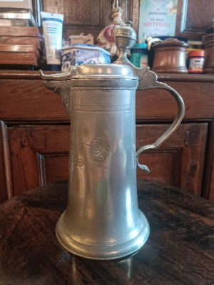 An 18th c. German pewter Flagon of tapering form, decorated with flowers and foliage around the monogram J. C. A and dated 1817.  Size 25 cm high.