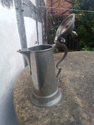 An 18th c.English spouted spire pewter flagon, 
O. E. W. S, half gallon, with plain tapering drum and beaded splayed footing, the double dome lid with acorn finial, a chair back thumb piece and broken- scroll handle with hooded ball terminal, hallmarks , Henry Joseph (PS5435).  Size 32 cm high.
Henry Joseph was born in London 1736 and died 1787)