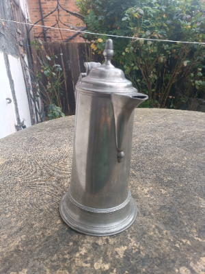 An 18th c.English spouted spire pewter flagon, 
O. E. W. S, half gallon, with plain tapering drum and beaded splayed footing, the double dome lid with acorn finial, a chair back thumb piece and broken- scroll handle with hooded ball terminal, hallmarks , Henry Joseph (PS5435).  Size 32 cm high.
Henry Joseph was born in London 1736 and died 1787)