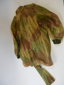 An original British Airborne Denison Smock dating from the post-1946 period. Commonly referred to as the Third Pattern or 1946 Pattern, this version retained many of the features of the wartime Second Pattern smock and remained in service with British and Commonwealth airborne forces for many years. The Denison Smock continued as standard combat clothing for the Royal Marines and the Parachute Regiment until the mid-1970s.

This example displays the distinctive screen-printed camouflage pattern, featuring a light sand-coloured base overlaid with broad green and reddish-brown brushstrokes. Characteristic post-war features include knitted cuffs, nickel-plated Newey press studs, a brass Swift half-zip with its original pendant pull, shoulder epaulettes, a wool-lined collar, and the distinctive rear fishtail, which fastens to the front using the original press studs.

The original internal label is still present, although it has faded through laundering and is no longer legible.

Presented in good overall condition, the smock exhibits honest service wear consistent with its age. It retains its original knitted cuffs and remains complete throughout, making it an excellent example with strong display appeal as well as being perfectly wearable.