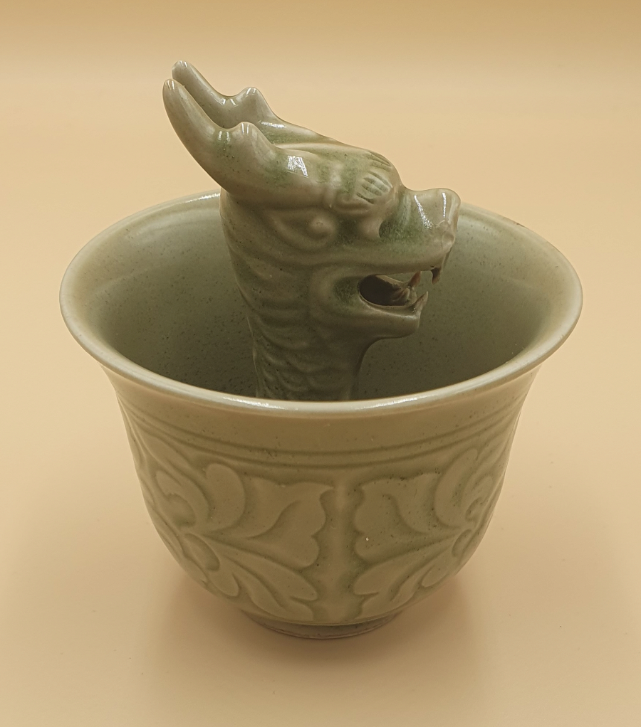 Discover our vintage porcelain dragon cups. Perfectly glazed in Celadon, these 'greedy cups' embody moderation & wisdom. Don't overfill, or it empties! Experience this magical ceramic art now.