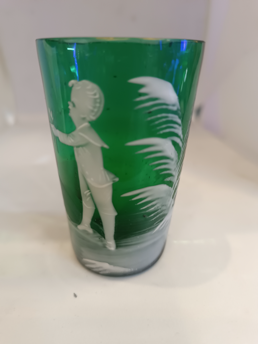 Discover the exquisite Mary Gregory emerald green shot tumbler glass. Perfect condition and featuring a unique design. Dive into antique elegance now.