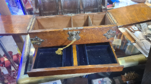 A Victorian oak tantalus, the three decanters restrained within a mirrored niche, hinged twin-covers enclosing provision for cigars and playing-cards, drawer to base, carrying handles to sides, applied with Gothic brass cut-card work. Centre decanter has a single chip on the neck.

Size: 33cm high, 37cm wide.