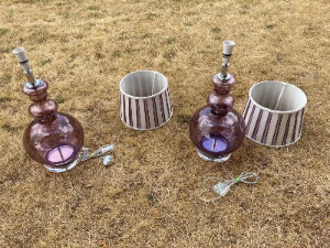 A stylish pair of brown glass table lamps, each featuring an elegant double-curved neck with tinted glass detailing, set upon a rounded glass base.

The lamps are complemented by designer striped silk shades, creating a sophisticated and decorative look. Both lamps have been PAT tested for electrical safety.

The shades are described as reproduction/vintage style and measure approximately 22 cm high × 26 cm diameter.

Overall lamp dimensions: approximately 59 cm high × 26 cm wide
Price: £395 for the pair
UK delivery: £40