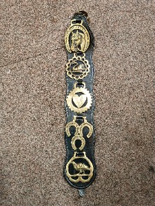 A vintage 5 horse brasses on the leather strap from one equestrian family.  Size  53 cm long.