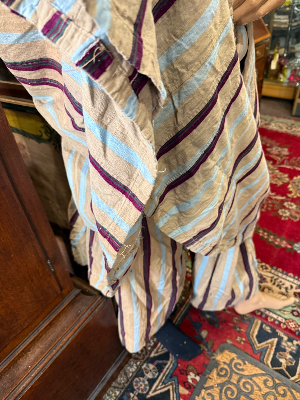 A striking mid-20th-century West African ceremonial ensemble, traditionally attributed to the Yoruba, comprising a voluminous agbada outer gown, ṣòkòtò trousers and fìlà cap.

The agbada is constructed from narrow strips of handwoven cloth in a natural cream ground, patterned with alternating blue and burgundy stripes. The front is extensively decorated with elaborate hand-worked embroidery, including large interlocking and quatrefoil motifs arranged symmetrically across the body of the gown.

Previous owner said he brought it back from West Africa in 1954 and identified it as belonging to the Yoruba.

Date: Mid-20th century, associated label dated 1954
Origin: Nigeria / West Africa
Attribution: Yoruba
Materials: Handwoven textile, embroidered decoration

Condition: Vintage condition consistent with age and traditional use. Please refer to photographs for individual areas of wear, marks, repairs or losses.