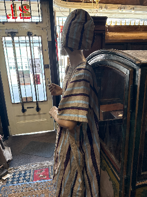 A striking mid-20th-century West African ceremonial ensemble, traditionally attributed to the Yoruba, comprising a voluminous agbada outer gown, ṣòkòtò trousers and fìlà cap.

The agbada is constructed from narrow strips of handwoven cloth in a natural cream ground, patterned with alternating blue and burgundy stripes. The front is extensively decorated with elaborate hand-worked embroidery, including large interlocking and quatrefoil motifs arranged symmetrically across the body of the gown.

Previous owner said he brought it back from West Africa in 1954 and identified it as belonging to the Yoruba.

Date: Mid-20th century, associated label dated 1954
Origin: Nigeria / West Africa
Attribution: Yoruba
Materials: Handwoven textile, embroidered decoration

Condition: Vintage condition consistent with age and traditional use. Please refer to photographs for individual areas of wear, marks, repairs or losses.