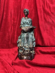 French bronze sculpture of a fruit-bearing goddess, circa 1920. The figure wears a gown with a green verdigris finish. Dimensions: 33 cm high × 15 cm wide × 14 cm deep.