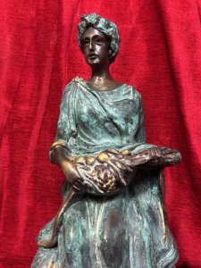 French bronze sculpture of a fruit-bearing goddess, circa 1920. The figure wears a gown with a green verdigris finish. Dimensions: 33 cm high × 15 cm wide × 14 cm deep.