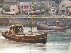 Original oil painting on board depicting a harbour with fishing boats, a canal waterway and houses. Intricate detail and vivid colours capture the waterfront beneath a stormy sky. Signed by Hong Kong-based artist WAN and presented in a cream wooden frame with a painted border.