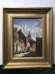 Original Dutch street scene oil painting on board by artist M Ives, presented in a gilt frame. The village view depicts cobbled streets and seven male and female figures in traditional dress, with a spired church in the background beneath a blue sky.