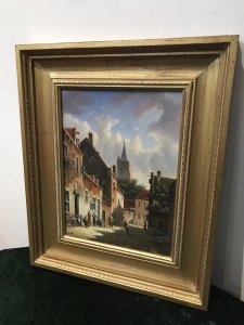 Original Dutch street scene oil painting on board by artist M Ives, presented in a gilt frame. The village view depicts cobbled streets and seven male and female figures in traditional dress, with a spired church in the background beneath a blue sky.