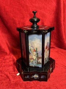 Antique Original Reuge Musical Cigarette Carousel Adorned With Painted Landscape Scenes Circa - Victorian 1890 Composition - Ebony Wood, Mother Of Pearl And Oils Listing Description Fine Quality Swiss Made Musical Cigarette Carousel Constructed In A Hexagonal Form. The Body Is Comprised Of Cylindrical Framework Hanging Six Doors Which Revolve (By Turning The Top Pinnacle CLOCKWISE To Open), Revealing Ornate Brass Individual Cigarette/Cigar Mounts. The Front Of Each Door Decorated With Fine Mother Of Pearl Inlays Intricately Over Painted With Quintessential Costal Town Landscape Scenes And Sailing Boats . Ornamental Scalloped Plinth Base Decorated With Floral Sprays Of Meadow Flowers To Match The Top Of The Carousel. Complete With Original Winding Key For Musical Element Which Plays Beautifully A Array Of Tunes. Video Available Of The Carousel Playing (Please Call If You Require The Video) Winding Keyhole On The Underside. Muiscal Switch On The Side Of The Carousel. Rare & Interesting Collectors Item. Condition - Very Good Antique Signs Of Wear To Paint Work Due To Age And Usage. In Good Working Order. Dimensions In Inches Height 11" Base Diam 7.5" For Further Pictures And Other Information Please Call 07376618513