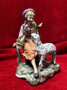 Capodimonte Porcelain Tale Of Boo Peep Figurine Circa- Vintage Composition - Hard Paste Porcelain. Listing Description Young Maiden Sitting On Picket Fence With Basket Of Apples And Lamb Companion Gazing Up For Apple Reward. Finely Detailed Porcelain Charming Subject. Dimensions In Cms Height 20cm X Width 14cm X Depth 15cm