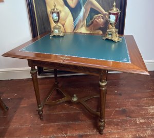 French Reproduction Louis XVI Style Writing Table With Leather Turnover Top Circa - Vintage Composition - Walnut Beautifully Decorative Top With Bands Of Kingwood/ Amboyna Wood Inlays And Central Floral Bouquet Motifs. The Table Top Opens Out Revealing A Green Floral Tooled Leather Writing Surface And Swivels To Reveal Hidden Compartments For Writing Paper/ Equipment Underneath. Delicate Legs With Brass Ormolu Mountings Supported By Bow Shaped Stretcher With Central Pinnacle. Dimensions In Inches Height 30 1/4" Width 26.5" Depth 18 3/4" Top Open 37" X 26.5"