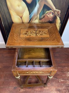 French Reproduction Louis XVI Style Writing Table With Leather Turnover Top Circa - Vintage Composition - Walnut Beautifully Decorative Top With Bands Of Kingwood/ Amboyna Wood Inlays And Central Floral Bouquet Motifs. The Table Top Opens Out Revealing A Green Floral Tooled Leather Writing Surface And Swivels To Reveal Hidden Compartments For Writing Paper/ Equipment Underneath. Delicate Legs With Brass Ormolu Mountings Supported By Bow Shaped Stretcher With Central Pinnacle. Dimensions In Inches Height 30 1/4" Width 26.5" Depth 18 3/4" Top Open 37" X 26.5"