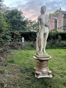 Roman Male Senator 'Augustas' Holding Scripture Set Upon Plinth Garden Showpiece Circa - VintageComposition - Reconstituted Stone Listing Description Standing Male Roman Senator Figure With Left Facing Head, Detailed Facial Features With Mid Length Hair And Headband, Partly Dressed In Draped Loin Cloth Set Over Chest For Modesty. Scripture In Left Hand, Whilst Right Hand Is Placed Upon Tree Stump. Bare Feet In Fine Detail Uponn Rocky Mound. Statue Stands On Circular Gilt Roman Pillar Pedestal. Condition - Excellent Signs Of Weathering To Statue Conducive To Age. Dimensions In Inches Height 40” without plinth Width Depth