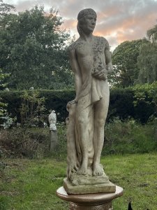 Roman Male Senator 'Augustas' Holding Scripture Set Upon Plinth Garden Showpiece Circa - VintageComposition - Reconstituted Stone Listing Description Standing Male Roman Senator Figure With Left Facing Head, Detailed Facial Features With Mid Length Hair And Headband, Partly Dressed In Draped Loin Cloth Set Over Chest For Modesty. Scripture In Left Hand, Whilst Right Hand Is Placed Upon Tree Stump. Bare Feet In Fine Detail Uponn Rocky Mound. Statue Stands On Circular Gilt Roman Pillar Pedestal. Condition - Excellent Signs Of Weathering To Statue Conducive To Age. Dimensions In Inches Height 40” without plinth Width Depth