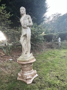 Roman Male Senator 'Augustas' Holding Scripture Set Upon Plinth Garden Showpiece Circa - VintageComposition - Reconstituted Stone Listing Description Standing Male Roman Senator Figure With Left Facing Head, Detailed Facial Features With Mid Length Hair And Headband, Partly Dressed In Draped Loin Cloth Set Over Chest For Modesty. Scripture In Left Hand, Whilst Right Hand Is Placed Upon Tree Stump. Bare Feet In Fine Detail Uponn Rocky Mound. Statue Stands On Circular Gilt Roman Pillar Pedestal. Condition - Excellent Signs Of Weathering To Statue Conducive To Age. Dimensions In Inches Height 40” without plinth Width Depth