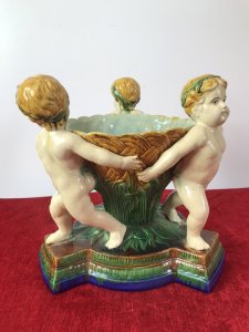Italian Majolica Trio Of Cherubs Centrepiece With Green And Yellow Overglaze. Origin - Rome Italy. Circa - Vintage Trio Of Detailed Posed Cherubs Holding Delicate Flower Urn With Ornate Stepped Pedestal Base. Stunning Display Piece For Table Or Collection. Fine Replica Of 18th Century Grand-tour Piece. Heavy Glazed Pottery Beautiful Quality In Perfect Condition. Dimensions In Inches Height 11” Width 10.5” Circumference 29.5” Weight Approx 12 Kg