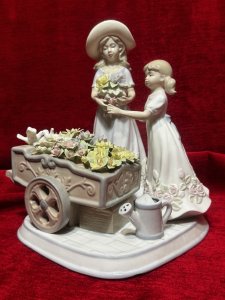 The Flower Harvest Porcelain Figurine By The Leonardo Collection Circa - Vintage Condition - Pristine Composition - Porcelain Listing Description Wonderfully Elegant Large Leonardo Collection Figurine Totle ‘The Flower Harvest’ Depicting A Mother And Daughter Picking Flowers From Decorative Flower Kart. Stamped On Base. Dimensions In Cms Height 26cm X Width22cm X Depth 22cm
