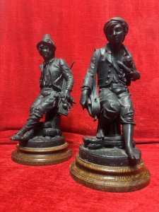 Cornelius & Baker Rare Pair Of Figural Statues The Organ Grinder & The Puppeteer Circa - Late 19th Century Composition - Cast Zinc Metal On Wood Plinth Bases Listing Description Pair of Rare Antique American Manufacturer Cornelius And Barker Figural Statues. The Statues Depict Street Musicians Specifically Titled 'The Organ Grinder' With A Monkey Under His Coat, And A Musician Holding A String Instrument With A Stringed Puppet Titled 'The Puppeteer'. Stunning Pair in Superb Detail And Wonderful Condition. Set Upon Solid Wood Cylindrical Plinth Bases. Dimensions In Inches Height 35cm X Width 19cm X Depth 17cm