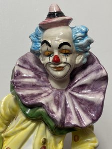 Magnificent Large Capodimonte Bright Glazed Circus Clown Figurine With Dog Companion. Circa - Vintage Composition - Glazed Porcelain Listing Description Large Stylised Hand Painted Circus Clown With Bold Face Paint, Blue Tufted Hair And Pointed Pink Hat. Oversized Double Flounced Neck Ruff Over Vibrant Yellow Spotted Coat. Orange Baggy Trouser With Comical Teared Hole At The Knee. This Magnificent Clown Holds Green Ball And Bugle Horn. A Fellow Dog Companion Sits Poised Upon The Circular Base With Blue Collar And Matching Hat. Wonderful Rare Piece For Collector Of Clowns \ Capodimonte And Circus Memorabilia. Condition - Used Sadly The Top Of The Bugal Has Been Damaged Please See Images. A Few Small Chips To Paint Visible Due To Age And Usage. This Does Not Detract From The Beauty Of The Piece But Is Reflective In The Price. Dimensions In Inches Height 20" Width 9" Depth 10"