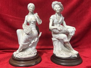 Pair Of Traditional Italianate Sitting Male/Female Capodimonte Style Figurines On Wood Plinths Circa - 1980 Composition - Porcelain on Wood Plinth Listing Description Wonderful Perfect Pair Of Italian Capodimonte Style Figurines. Female Sitting On Tree Stump With Floral Basket, Holds Rose In left Hand. Male Seated On Tree Stump Wears Straw Hat Holding Fruit Basket. Both Signed On Base By Artist A Berni And ADT ITALY With Capodimonte Style Ink Mark. Set Upon Polish Wood Base Plinths. Dimensions In Cms Male Height 32cm X Width 16cm X Depth 20cm X Base Diam 18cm Female Height 31.5cm X Width 16cm X Depth 14cm x Base Diam 18cm