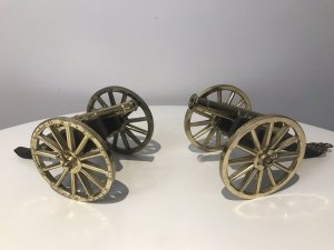A Pair Of Vintage Military Gun Cannons In The Napoleonic Style Solid Guilt Bronze Metal Barrels With Spoke Wheels And Towing Hooks To Be Pulled By Horses At Battle Exceptional Detail With Hardwood Gun Carriage Quality Replica Guns Heavy And Handmade By Craftsman In England Collectors Items Dimensions In Inches Length 7 1/4 “ Wheels Height 4” Gun Barrel Length 4 3/4
