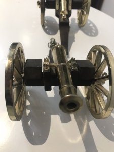 A Pair Of Vintage Military Gun Cannons In The Napoleonic Style Solid Guilt Bronze Metal Barrels With Spoke Wheels And Towing Hooks To Be Pulled By Horses At Battle Exceptional Detail With Hardwood Gun Carriage Quality Replica Guns Heavy And Handmade By Craftsman In England Collectors Items Dimensions In Inches Length 7 1/4 “ Wheels Height 4” Gun Barrel Length 4 3/4