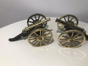 A Pair Of Vintage Military Gun Cannons In The Napoleonic Style Solid Guilt Bronze Metal Barrels With Spoke Wheels And Towing Hooks To Be Pulled By Horses At Battle Exceptional Detail With Hardwood Gun Carriage Quality Replica Guns Heavy And Handmade By Craftsman In England Collectors Items Dimensions In Inches Length 7 1/4 “ Wheels Height 4” Gun Barrel Length 4 3/4