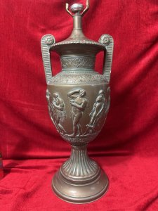 Neo-Classical Style Roman Goddess Bronzed Urn Lamp Stand Circa - 1970 Composition - Metal With Gesso Listing Description Exceptionally Ornate Neo Classical Style Double Handled Urn Lamp Stand. Floral Filigree Boarder Patterns Around Vase Neck And Body. The Central Body Of The Vase Has Many Grecian God And Goddess Figures Dancing And Playing Instruments. Heavy Item. Bulb Mount On Top And Wire Hole At Base. Needs Rewire For Use. Dimensions In Cms Height 55cm X Width 21cm At handles x Base Diam 20cm