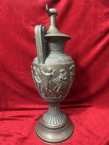 Neo-Classical Style Roman Goddess Bronzed Urn Lamp Stand Circa - 1970 Composition - Metal With Gesso Listing Description Exceptionally Ornate Neo Classical Style Double Handled Urn Lamp Stand. Floral Filigree Boarder Patterns Around Vase Neck And Body. The Central Body Of The Vase Has Many Grecian God And Goddess Figures Dancing And Playing Instruments. Heavy Item. Bulb Mount On Top And Wire Hole At Base. Needs Rewire For Use. Dimensions In Cms Height 55cm X Width 21cm At handles x Base Diam 20cm