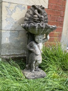Classical Cherub Holding Scallop Shell Basin With Dolphins Bird Bath. Circa - Vintage Composition- Reconstituted Stone Condition- Used Original Weathered Beautifully Detailed Cherub Stands Against Scrolled Column Carefully Balancing A Scallop Shell Basin Above His Head With Ornamental Dolphins Fountain Design. Refined Facial Features With Eloquent Hands. An Exceptional Vintage Piece Inspired By French 18th Century Architecture. Stunning Garden Feature For Attracting Birds And Wildlife. Heavy Item. Provenance Purchased From 18th Century Stately Home Walled Market Garden, Derby. Dimensions In Cms Height 86cm Width 42cm Depth 29cm