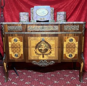 French Régency Ormolu Mounted & Marquetry Inlaid Breakfront Marble Top Commode Circa - 1980 Composition - Sold Wood Frame With Precious Wood Inlay/ Marble Top Listing Description Impeccable Fine Quality French Régence Style Break Front Commode, With Canted Corners And An Abundance Of Ormolu Mounts. Solid Carrera Marble Top With Rich Grain Work. Front Face Comprised Of Richly Decorated Ormolu Top Mount Over Two Drawers Adorned With Elaborate Precious Wood Inlays To Include, Rose Wood, Satin Wood, Amboyna Wood And Fruit Wood. A Showpiece Of Central Cameo, Inside A Winged Putti Playing Loot, Encased By A Elegant Wheat Sheaf Frame, Held By Ribbon Inside Geometric Boarder. Either Side A Symbolic Masterpiece Of Parquetry Themed Motifs. Both Drawers Complete With Brass Ormolu Garland Drop Handles. Matching Side Elevations With Delicate Floral Motifs Inlays And Mounts. Cabinet Set Upon Splayed Legs. Dimensions In Inches Height 31.5" X Width 43" X Depth 18.5" Provenance Purchased From Parisian Chateau Private Collector. Heavy/Fragile Item Requires Hand Delivery. For Any Further Information Please Call The Curator On 07707 488566 Thank-you.