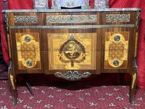 French Régency Ormolu Mounted & Marquetry Inlaid Breakfront Marble Top Commode Circa - 1980 Composition - Sold Wood Frame With Precious Wood Inlay/ Marble Top Listing Description Impeccable Fine Quality French Régence Style Break Front Commode, With Canted Corners And An Abundance Of Ormolu Mounts. Solid Carrera Marble Top With Rich Grain Work. Front Face Comprised Of Richly Decorated Ormolu Top Mount Over Two Drawers Adorned With Elaborate Precious Wood Inlays To Include, Rose Wood, Satin Wood, Amboyna Wood And Fruit Wood. A Showpiece Of Central Cameo, Inside A Winged Putti Playing Loot, Encased By A Elegant Wheat Sheaf Frame, Held By Ribbon Inside Geometric Boarder. Either Side A Symbolic Masterpiece Of Parquetry Themed Motifs. Both Drawers Complete With Brass Ormolu Garland Drop Handles. Matching Side Elevations With Delicate Floral Motifs Inlays And Mounts. Cabinet Set Upon Splayed Legs. Dimensions In Inches Height 31.5" X Width 43" X Depth 18.5" Provenance Purchased From Parisian Chateau Private Collector. Heavy/Fragile Item Requires Hand Delivery. For Any Further Information Please Call The Curator On 07707 488566 Thank-you.