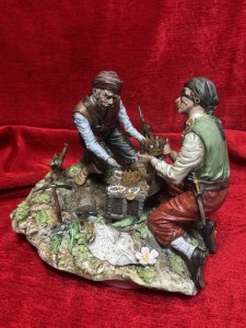 Large Italian Capodimonte Porcelain Figurine 'The Pirates Hidden Treasure' Signed By Artist Circa - 1940 Composition - Hard Paste Porcelain Listing Description Highly Renowned Capodimonte Collectable Showpiece. This Rare Subject Is An Exceptional Capodimonte Specimen. The Fine Quality Evident From The Realism Captured In The Finer Details Including; Faces, Hands, Fabric Movement In Clothes As Well And The Surrounding Flora And Fauna, Just To Name A Few. The Figure Depicts Two Pirates During Their Moment Of Discovery Opening A Large Wooden Treasure Chest, Cascading With Gold, Pearls And Precious Stones. One Of The Pirates Has A Metal Claw As A Hand, Exactly As You Would Expect Of A Pirate! The Treasure Map And Pick Axe A Foot Whilst They Glaze At The Prize. Signed By Artist. True Capodimonte Collectors Figurine. Dimensions In Cms Height 22cm X Width 29cm X 24 Depth For Further Information Please Enquire Direct On 07707 488566 Thank-you