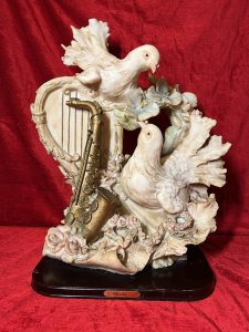 Large Italianate Romantic Turtle Doves & Instrumental Showpiece On Wood Plinth Signed Circa - 20th Century Composition - Resin Listing Description Wonderful Large Elaborate Italianate Centrepiece Depicting Pair Of Turtle Doves Entwined Amongst Musical Instruments And Vines Of Pink Roses And Pale Blue Orchids. The Turtle Doves Are Posed With One Nestled On Top Of A Strung Harp Gazing Downward At The Other Perched Upon A Whimsical Books Of Literature Next To Gilt Saxophone. An Abundance Of Flowers Flow In A Ornamental Bouquet From The Base Of The Sculpture Entwining All Elements. A Head Of Winged Cherub Is Visible Under The Top Dove On Both Front And Back Elevations. Fine Quality Hand Painted Sculpture Showpiece Can Be Admired From All Elevations. Set Upon Polished Mahogany Plinth With Front Plaque Reads 'Huda Italy' & Stamped On Back Elevation. Provenance Actual Showpiece Used As Decorative Prop In The Film 'Victoria'. Now Part of Lord Hill Museum Private Collection. For Further Information Regarding Any Of Our Stock Please Call 07376 618513 Thank-You Dimensions In Inches Height 20.5" Width 17" Depth 9"