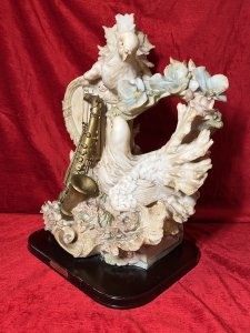 Large Italianate Romantic Turtle Doves & Instrumental Showpiece On Wood Plinth Signed Circa - 20th Century Composition - Resin Listing Description Wonderful Large Elaborate Italianate Centrepiece Depicting Pair Of Turtle Doves Entwined Amongst Musical Instruments And Vines Of Pink Roses And Pale Blue Orchids. The Turtle Doves Are Posed With One Nestled On Top Of A Strung Harp Gazing Downward At The Other Perched Upon A Whimsical Books Of Literature Next To Gilt Saxophone. An Abundance Of Flowers Flow In A Ornamental Bouquet From The Base Of The Sculpture Entwining All Elements. A Head Of Winged Cherub Is Visible Under The Top Dove On Both Front And Back Elevations. Fine Quality Hand Painted Sculpture Showpiece Can Be Admired From All Elevations. Set Upon Polished Mahogany Plinth With Front Plaque Reads 'Huda Italy' & Stamped On Back Elevation. Provenance Actual Showpiece Used As Decorative Prop In The Film 'Victoria'. Now Part of Lord Hill Museum Private Collection. For Further Information Regarding Any Of Our Stock Please Call 07376 618513 Thank-You Dimensions In Inches Height 20.5" Width 17" Depth 9"